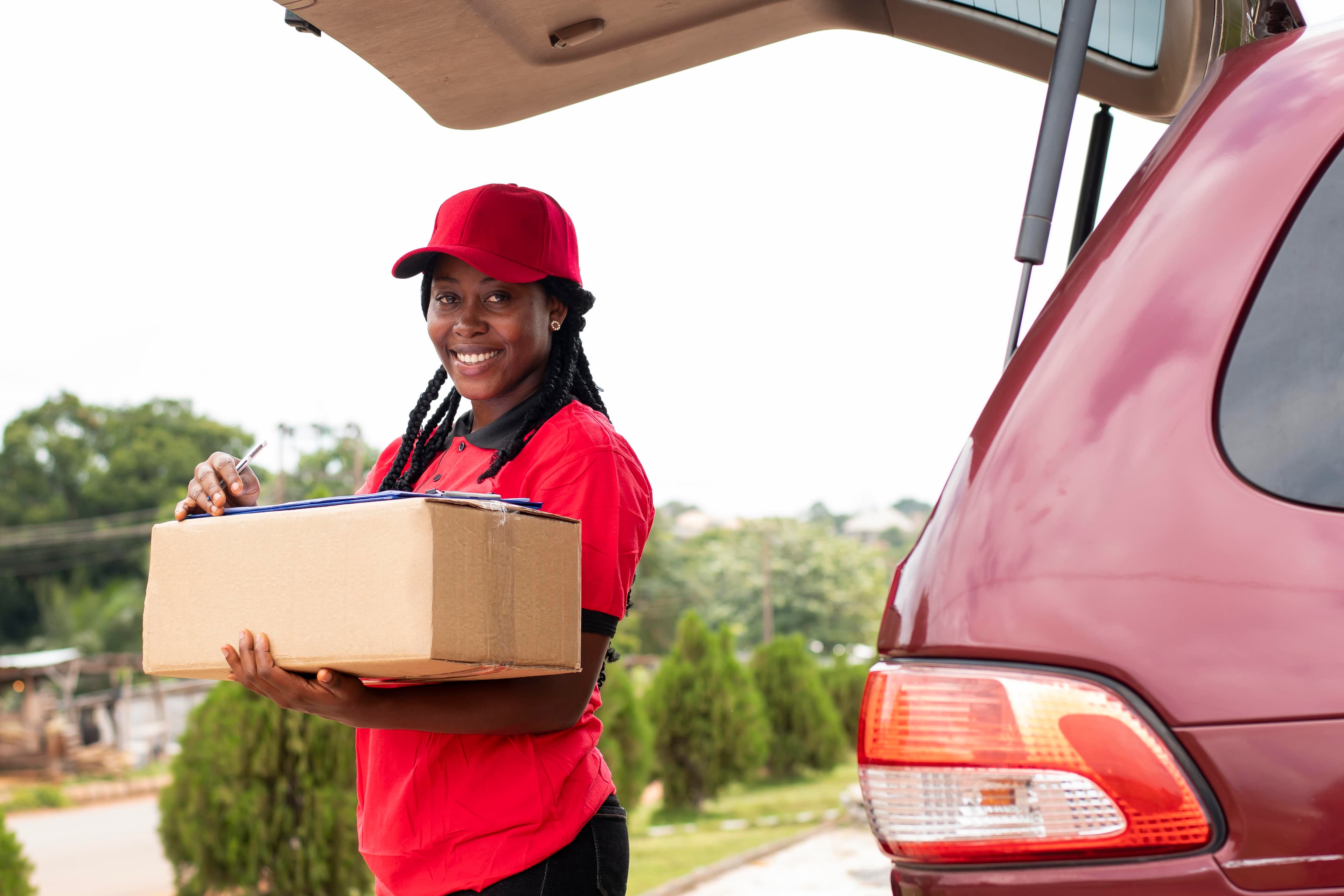 black female courier carrying packages looking delivery address city
